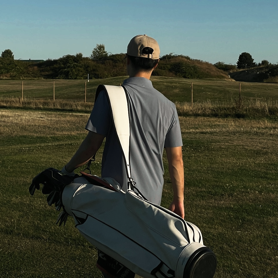 Man walking on a golf course carrying a golf bag